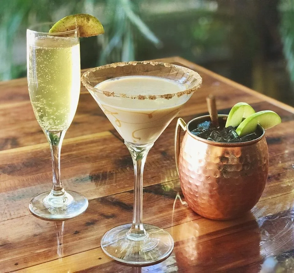 A champagne flute, a martini glass and a copper mug with lime, lined up on the bar