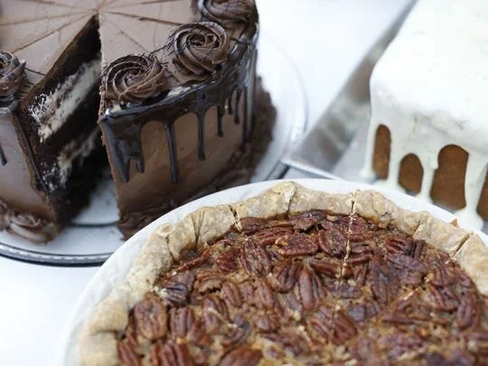 A slice of chocolate layer cake beside a pecan pie