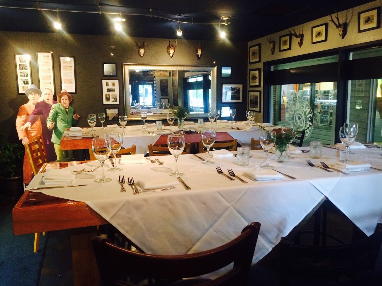 A dining room laid with white linen and glassware, paintings on the walls and doors open to the garden