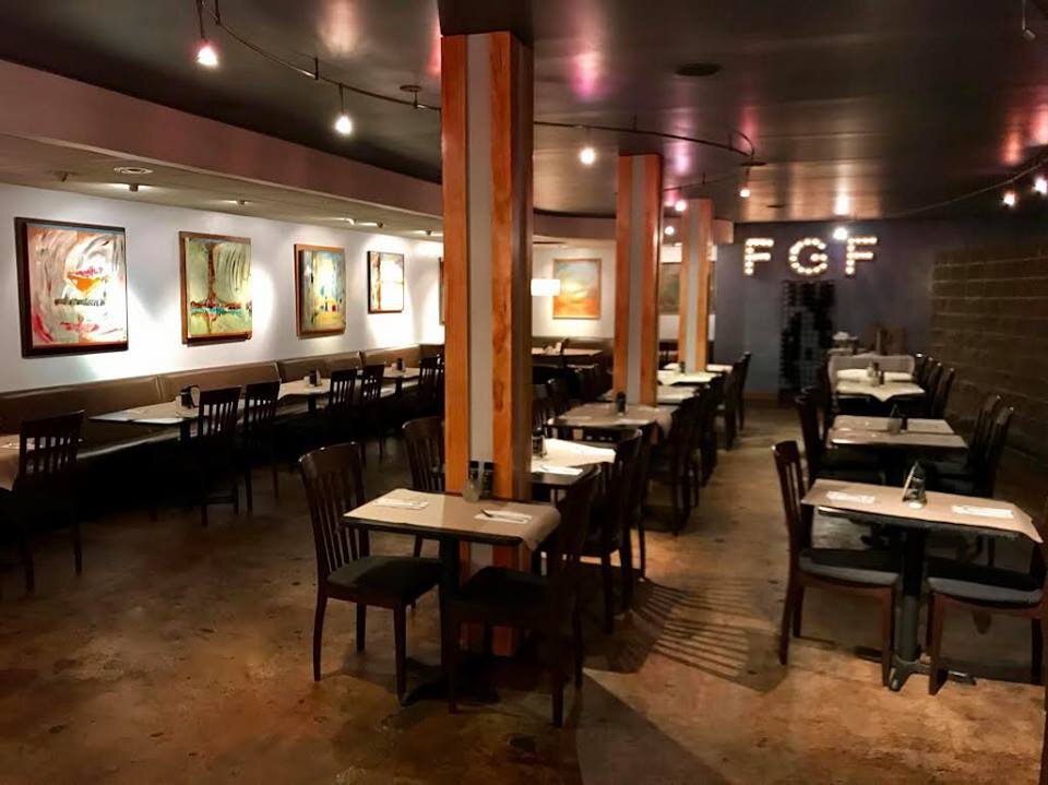 The main dining room with tables set under framed paintings and the letters F G F on the far wall