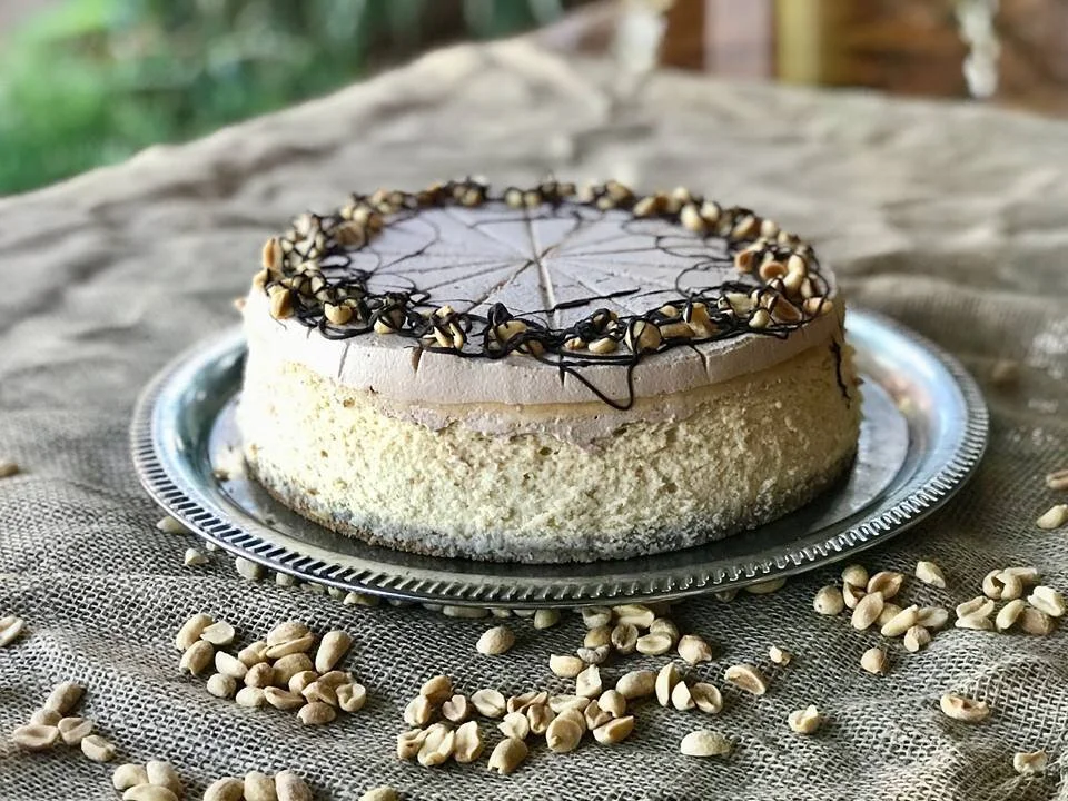 A pale cake edged in chopped nuts on a silver platter, scattered with nuts