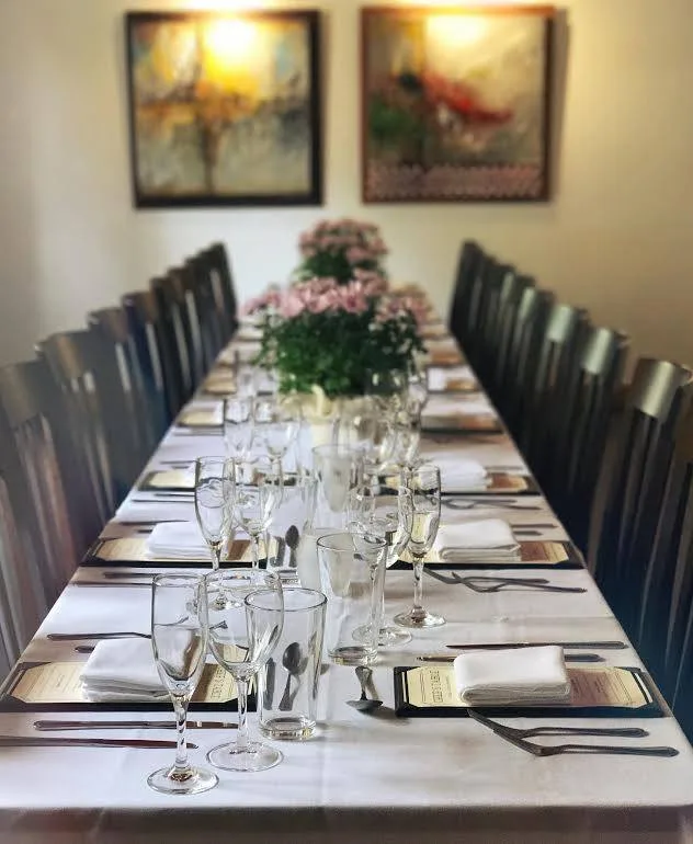 A long table in the private room, set with wine glasses and low flowers