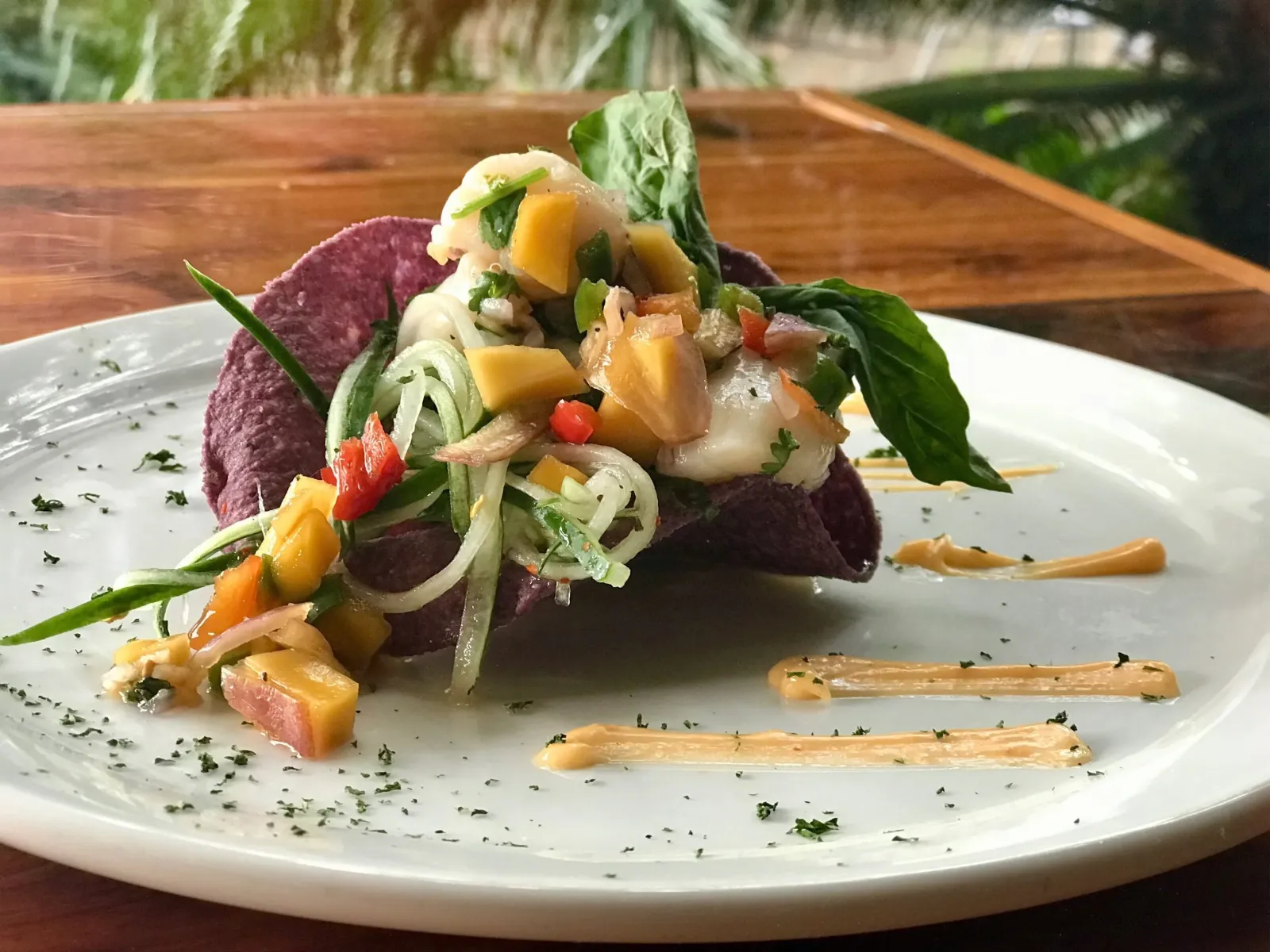 A salad of greens, peach and blue tortilla chips served in a crisp tortilla bowl